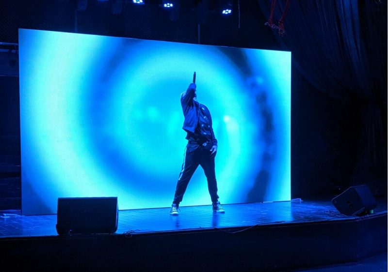 Image of Performer standing in front of large LED Display