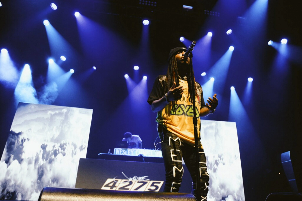 Image of American singer and rapper Jacquees performing on stage lit by LED panels